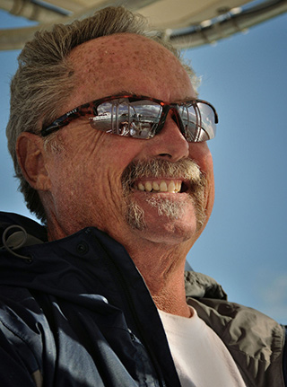 Photo portrait of Captain Ron on his boat with reflections in his sunglasses by Allen Moore.