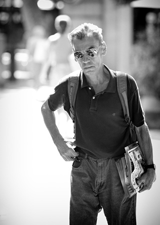 Black and white portrait of gray-haired man with sunglasses on the street by Alex Lagarejos.