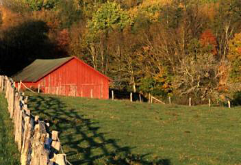 Wooden fence and shadows leading the eye to a red barn by Andy Long.