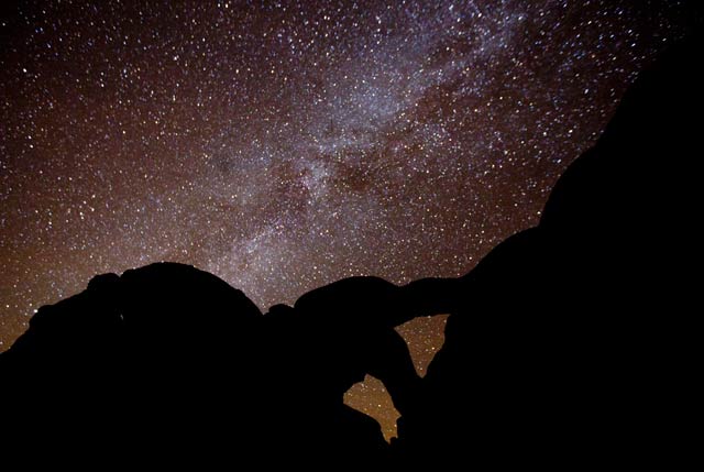 Star photography: Milky Way and lots of stars with silhouetted rock formations in foreground at Arches National Park, Utah by Andy Long.
