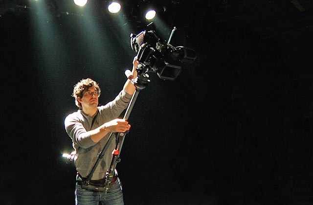 Product Review of hipjib. Man with hipjib around his waist - booming with an extended tripod and video camera.