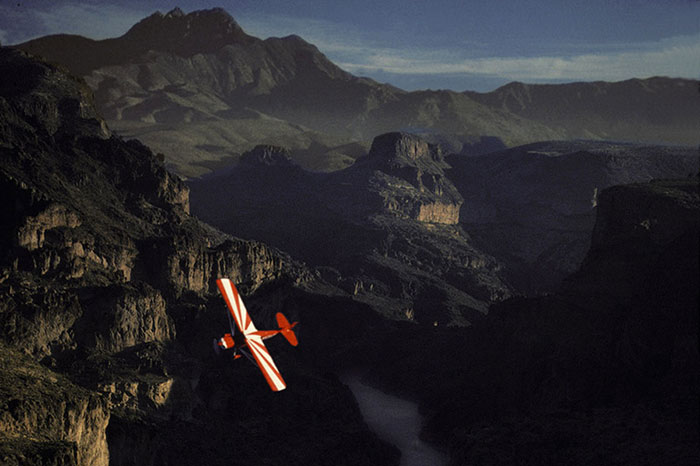 Photo of small plane flying over mountainous Sonora Desert, Arizona by Gert Wagner