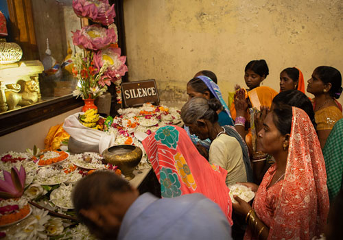 Photo of pilgrims presenting offerings to Buddha at Mahabodhi Temple, Bodhgaya, India by Nico DeBarmore.