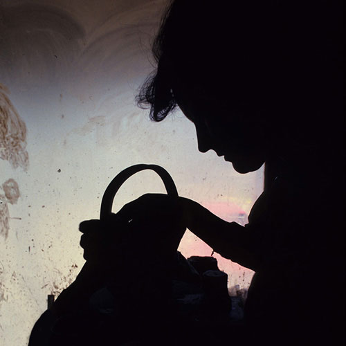 Silhouette of woman making clay pot with window light by Noella Ballenger