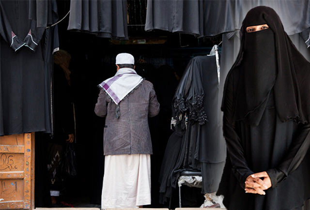 Yemeni clothing: A woman in a black balto and a man in traditional Yemeni clothing enters a balto shop by Maarten de Wolf.