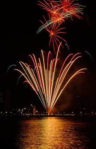 Multiple fireworks bursts reflected in the river by Marla Meier.