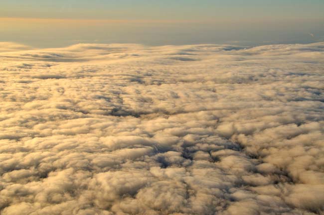 Aerial photo of the top of clouds with golden light by Allen Moore.