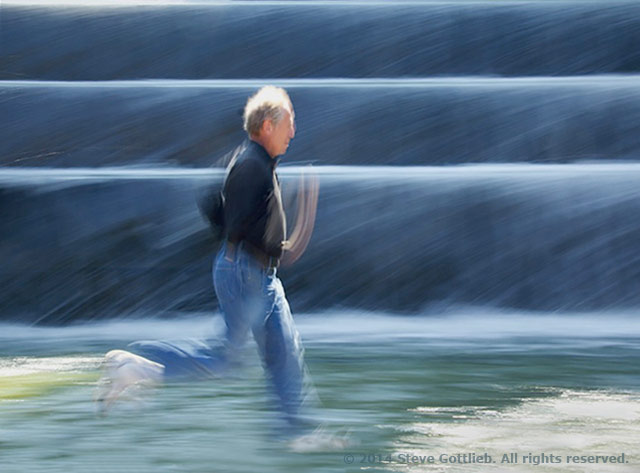 Image of man running along water created by panning with the subject by Steve Gottlieb.