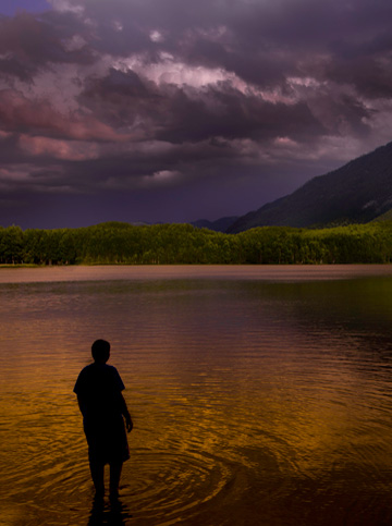 Man standing on edge of lake in Alaska by Michael Leggero.