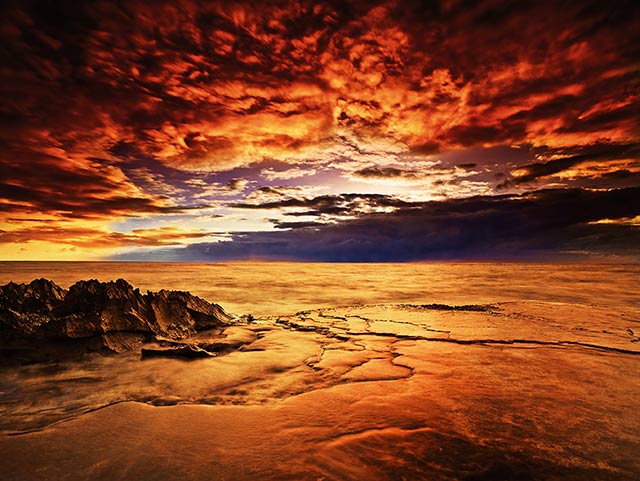 Koholina: orange, red and gold seascape iimage made at sunset at the shore of Oahu, Hawaii by Jeff Mitchum.