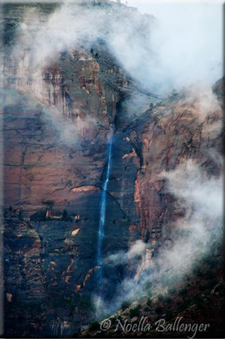 Image of a tall waterfall and storm coming in over rock formations in Zion National Park in Utah by Noella Ballenger.