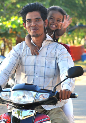 Photo of little girl & Dad on scooter by Ron Veto