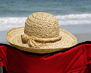 Protect your face from UV rays: Image of straw hat, chair and surf at Jacksonville Beach, Florida by Marla Meier.
