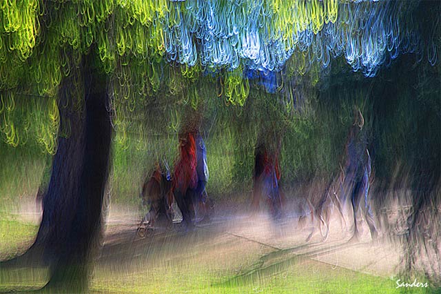Photo Impressionism technique: image of people on a path between trees where camera shake and sunlight streaming through the leaves resulted in bright loops of light by Gerald Sanders.