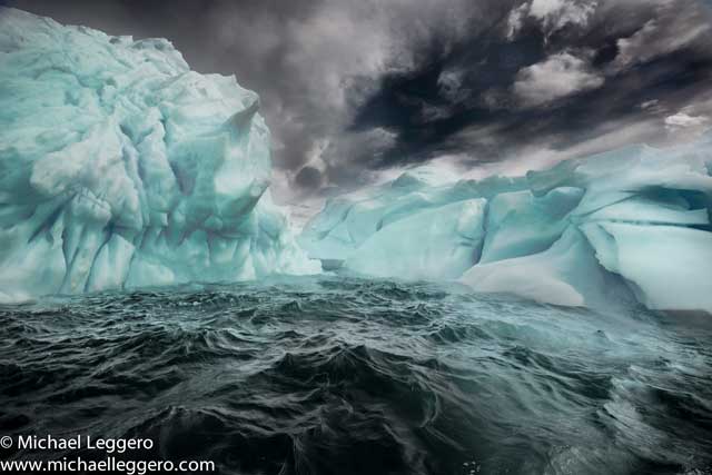 Dark stormy skies over rough seas an iceberg in Antarctica by Michael Leggero.