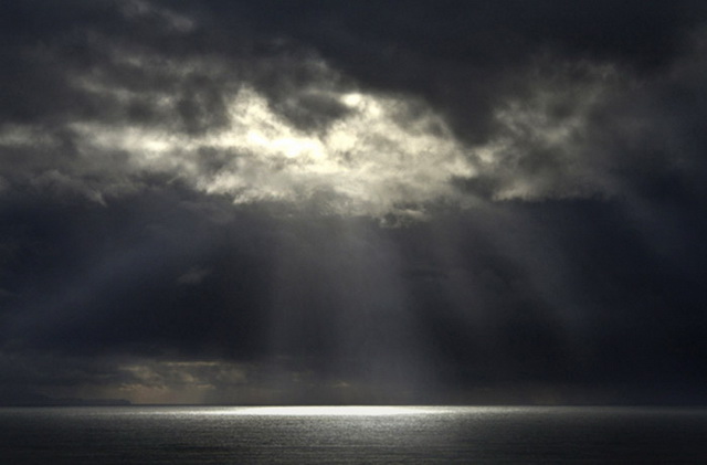Photo of light beams through clouds to top of ocean by Noella Ballenger
