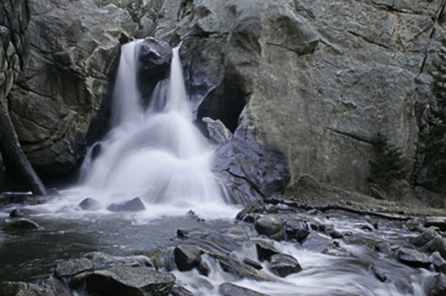 Landscape photo of a waterfall between the rocks using slow shutter speed by Andy Long.
