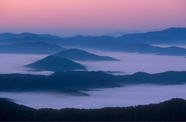 Landscape image of hills and water in the fog at sunrise by Andy Long.