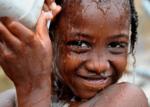Photo of girl pouring water over self for shower at Port-au-Prince, Haiti
