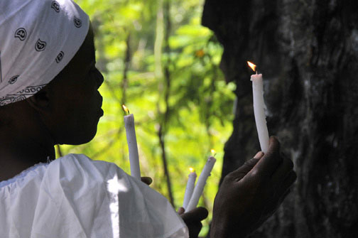 Photo of pilgrim lighting candle during the Saut d'Eau annual purification pilgrimage in Haiti