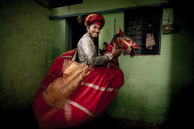 Motion is shown as a young man in a colorful horse costume acts before a festival in New Delhi, India by Harry Fisch.