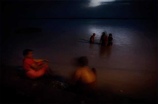 Motion blur is used to show women preparing the prayers next to the Ganges in Varanasi, India by Harry Fisch.
