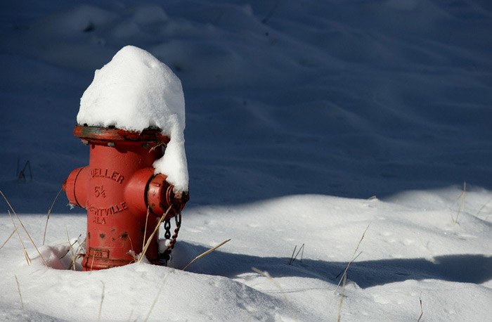 Red fire hydrant with snow piled on top by Andy Long.