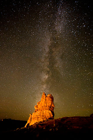Image of the Milky Way behind a lit rock formation by Andy Long.