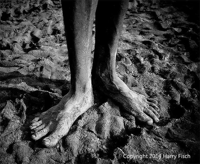Image of feet covered with dried mud at the salt mines in India by Harry Fisch.