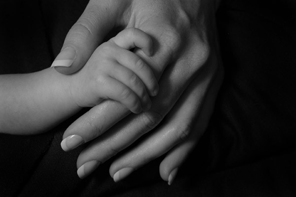 Black and white photo of hands of mother and baby by Monica von Stackelberg