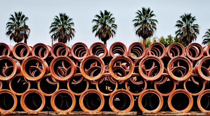 Photo of clay pipes and palm trees at the Gladding, McBean Terra Cotta Factory by Robert Hitchman